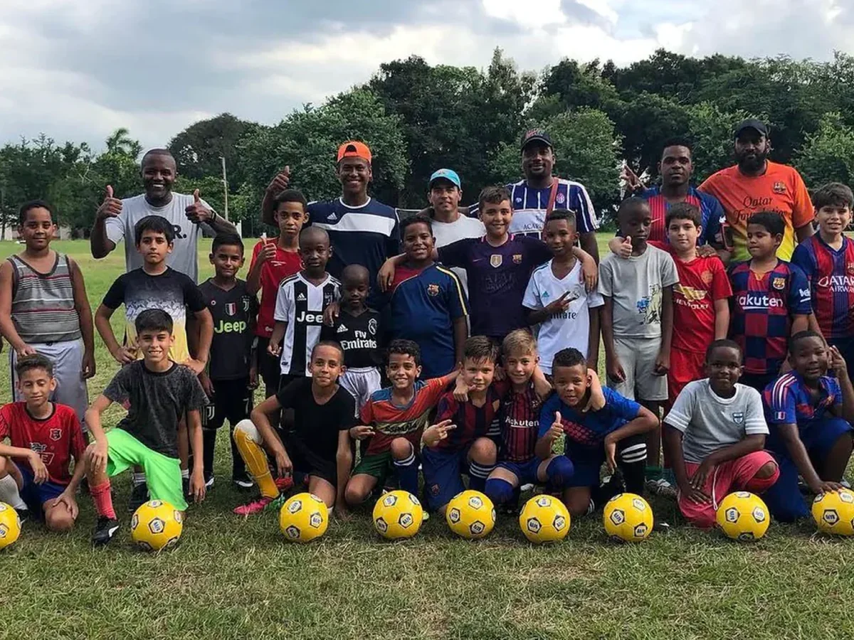 Large group of youth players and coaches gathered on a grass field in Cuba